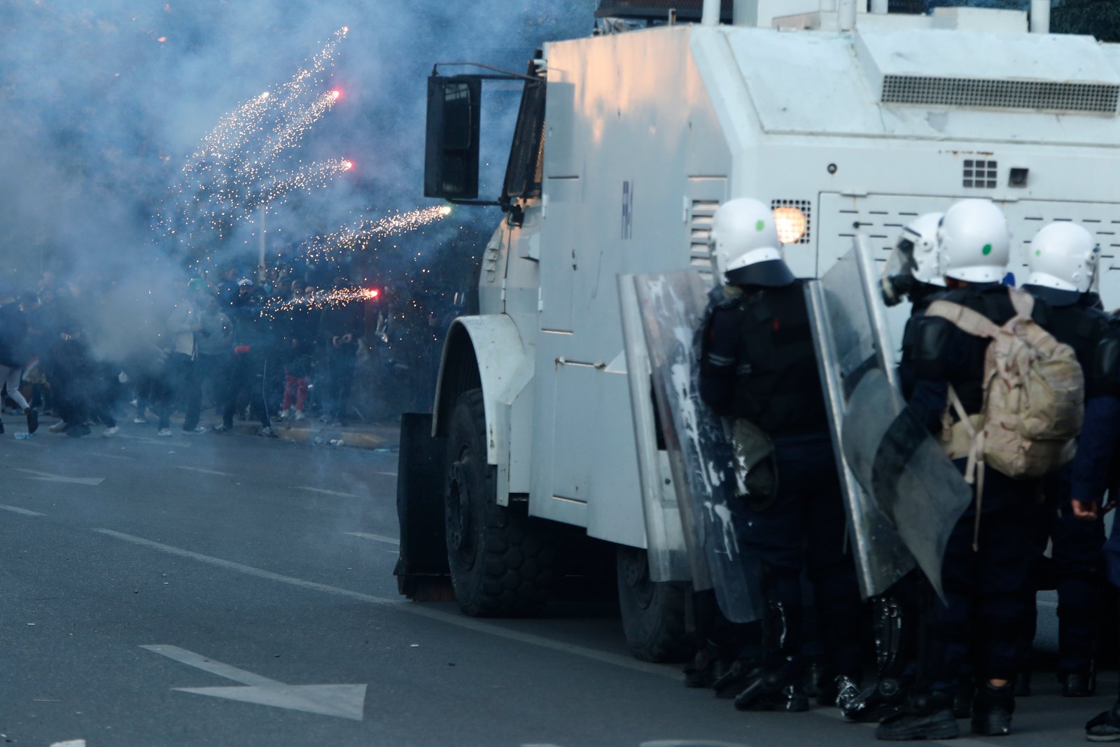 Antidisturbios se protegen tras un cañón de agua mientras los manifestantes lanzan pirotecnia, en Tirana, el 18 de octubre. Foto: Boris Grdanoski / AP.